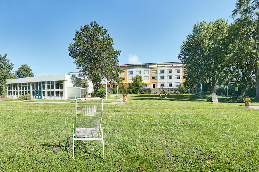 Ein Liegestuhl auf der Wiese mit der Klinik Wendelstein im Hintergrund